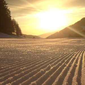 Piste fraîchement damée au lever du soleil aux Paccots